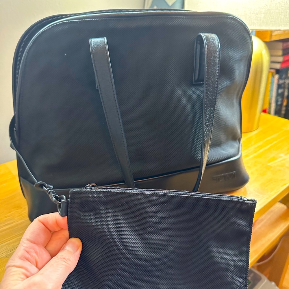 Tumi handbag with zipper pouch and double zipper closure.